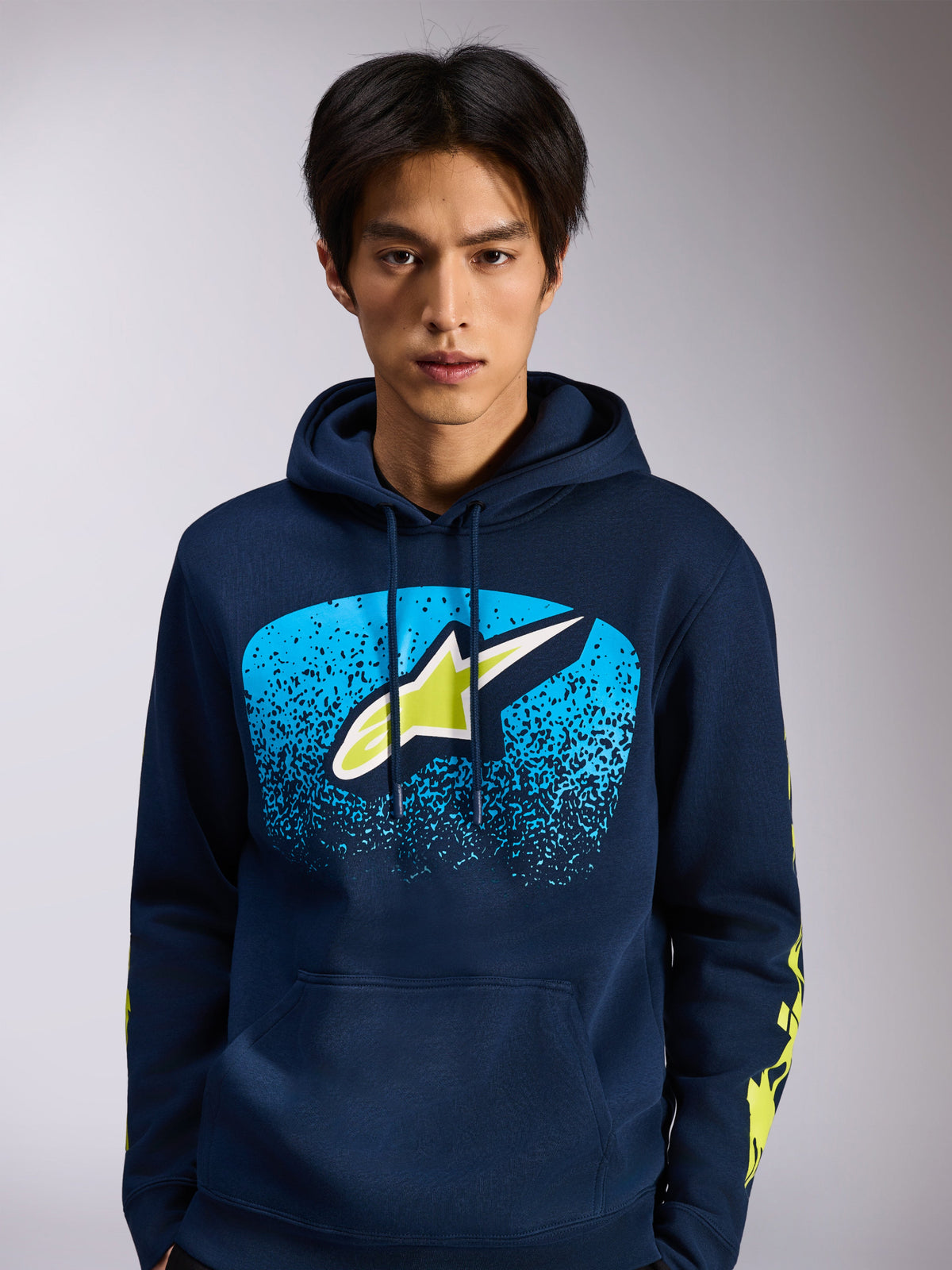 Alpinestars Obsessed Hoodie, navy blue pullover fleece, front Astars logo with blue MX gradation and lime green accents, yellow wordmark logos on sleeves, casual motorsport-inspired streetwear
