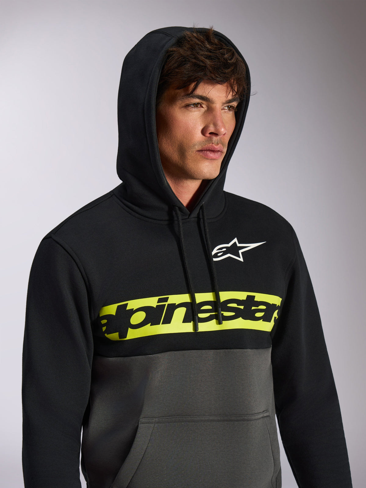 Alpinestars Parallel Hoodie, casual color-blocked streetwear, black top and gunmetal grey bottom, neon yellow chest band with black Alpinestars word logo, white Astars logo, hooded pullover with drawstring