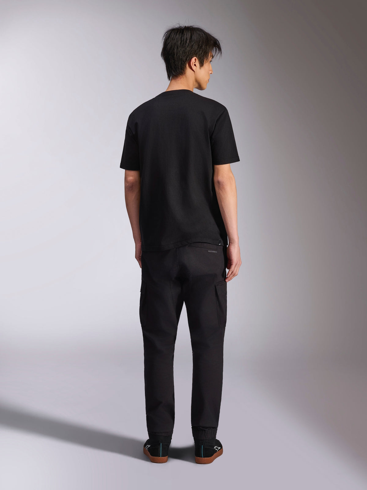 Alpinestars Noka CSF Tee, Short Sleeve T-Shirt, Black, back view of model wearing the tee with black pants and sneakers, casual motorsport streetwear style