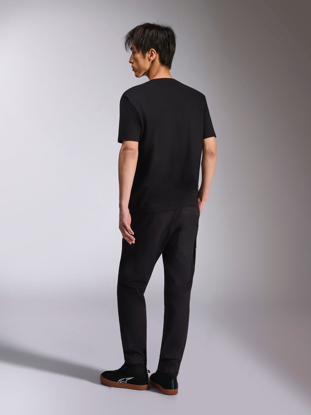 Alpinestars Noka CSF Tee, Short Sleeve T-Shirt, Black, back view shown on model, paired with black pants and casual sneakers, minimalist motorsport streetwear