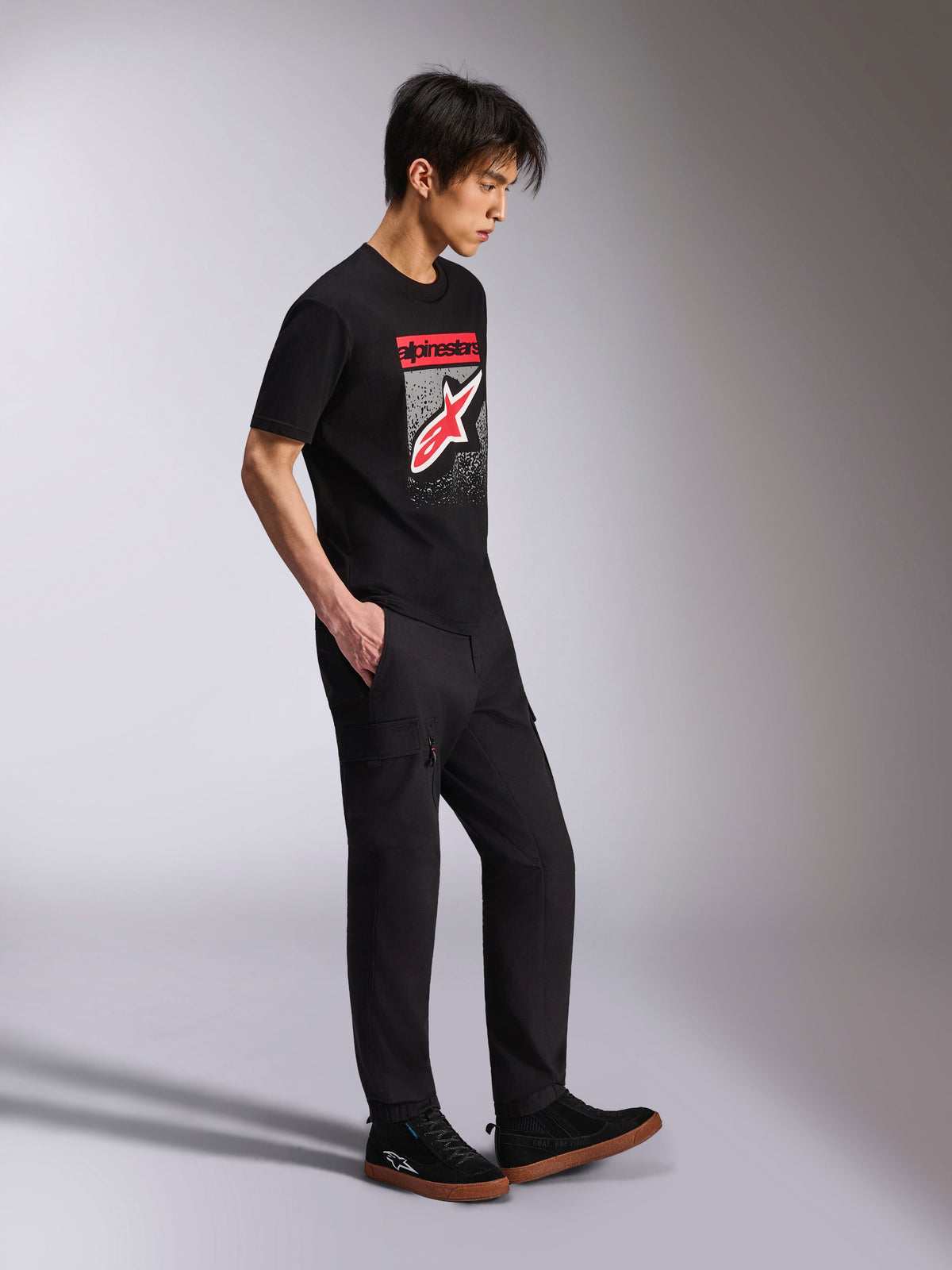 Alpinestars Noka CSF Tee, Short Sleeve T-Shirt, Black, Front Astars Logo with red and white MX gradation, worn with black cargo pants and sneakers, casual motorsport-inspired streetwear