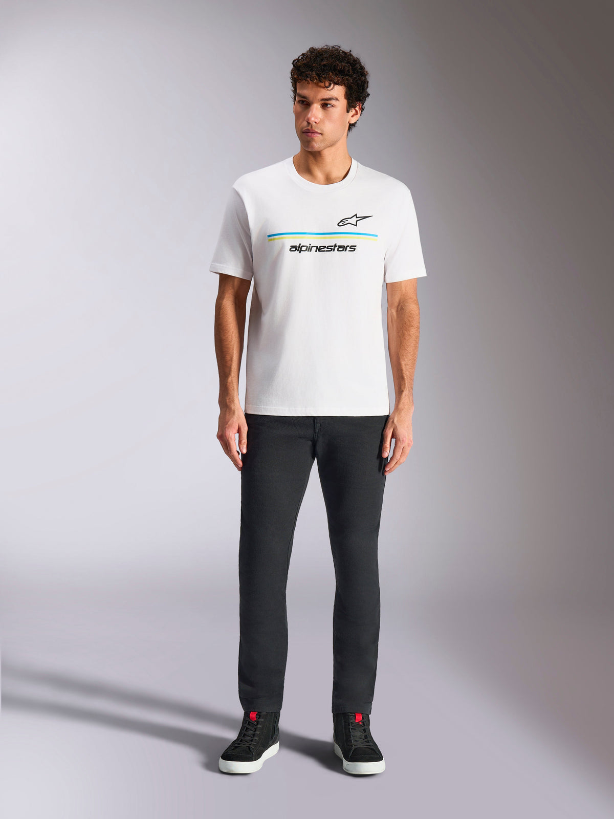Alpinestars Lanes CSF Tee, Short Sleeve T-Shirt, White, blue and yellow stripe logo graphic, worn by model with black pants and sneakers, casual motorsport streetwear