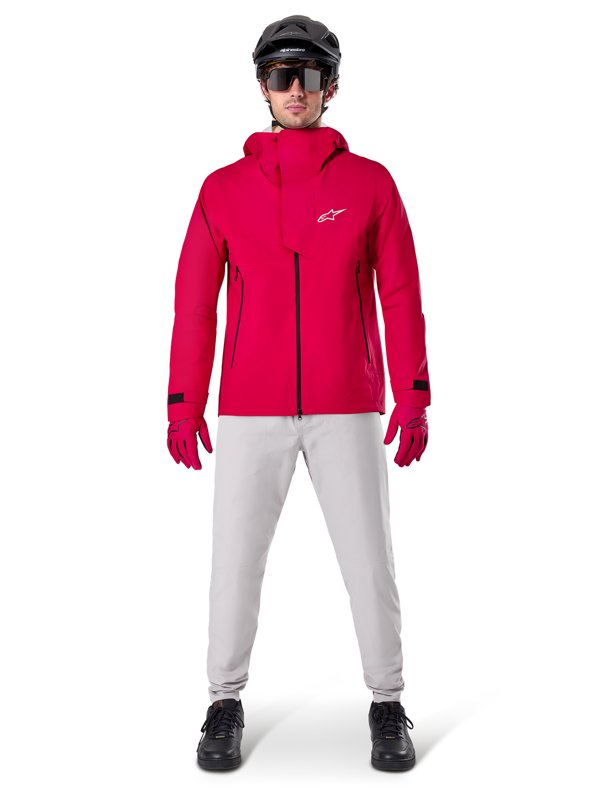 Alpinestars A-Dura Elite Waterproof Jacket, Red Fluo, technical mountain bike jacket worn with a black MTB helmet, sunglasses, matching red gloves, and light grey pants, full-body view of all-weather cycling gear