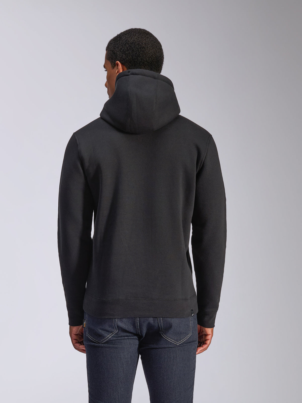 Alpinestars Blaze V3 Hoodie, rear view of black pullover fleece hoodie, casual streetwear, featuring ribbed cuffs and hem, jersey-lined hood, worn with dark blue jeans