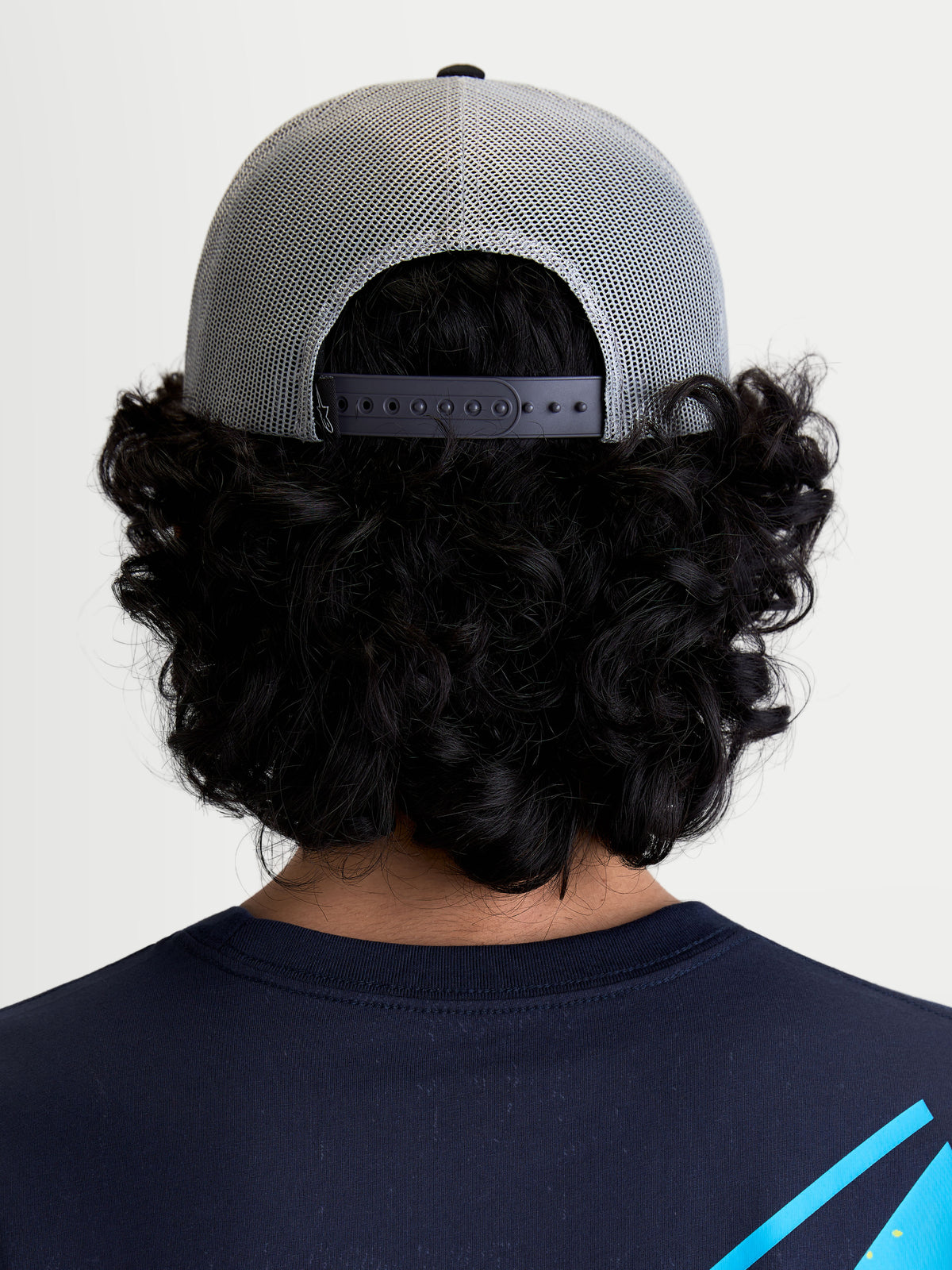 Alpinestars Gravel Trucker Hat, Gray and Black Sportswear Trucker Cap, rear view on model showing the breathable poly mesh back and adjustable snapback closure for a personalized fit.