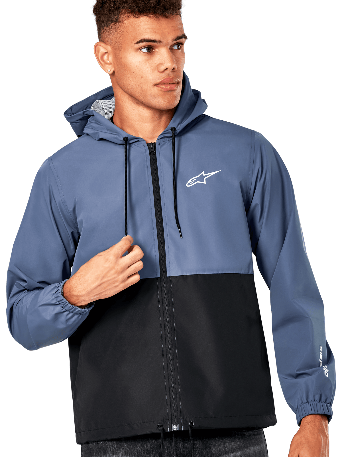 Male model wearing Alpinestars Speeder Windbreaker Jacket, Slate Blue and Black color-blocked design, hooded with black drawcords, white logo on chest, casual motorsport-inspired windbreaker