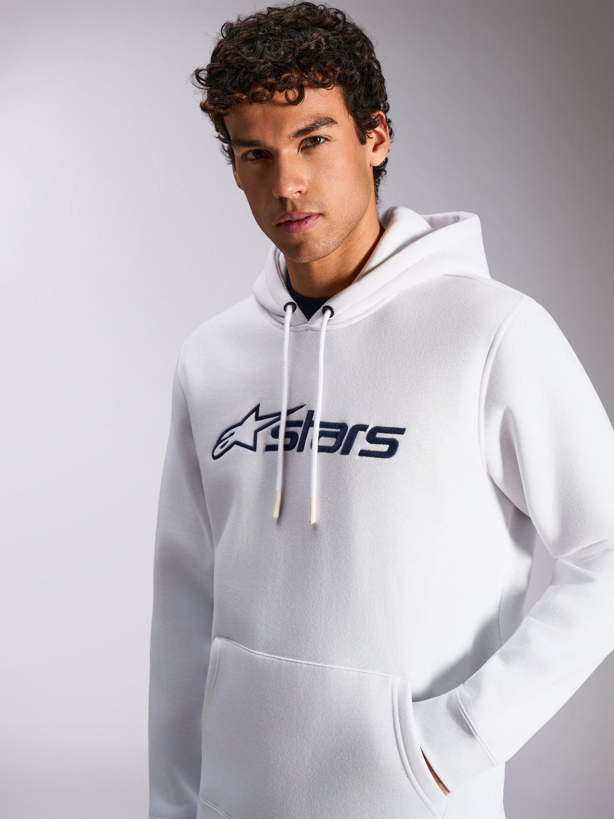 Alpinestars Blaze V3 Hoodie, White and Navy, worn by male model, casual sportswear, front navy Alpinestars logo, drawstring hood, kangaroo pocket, modern lifestyle design
