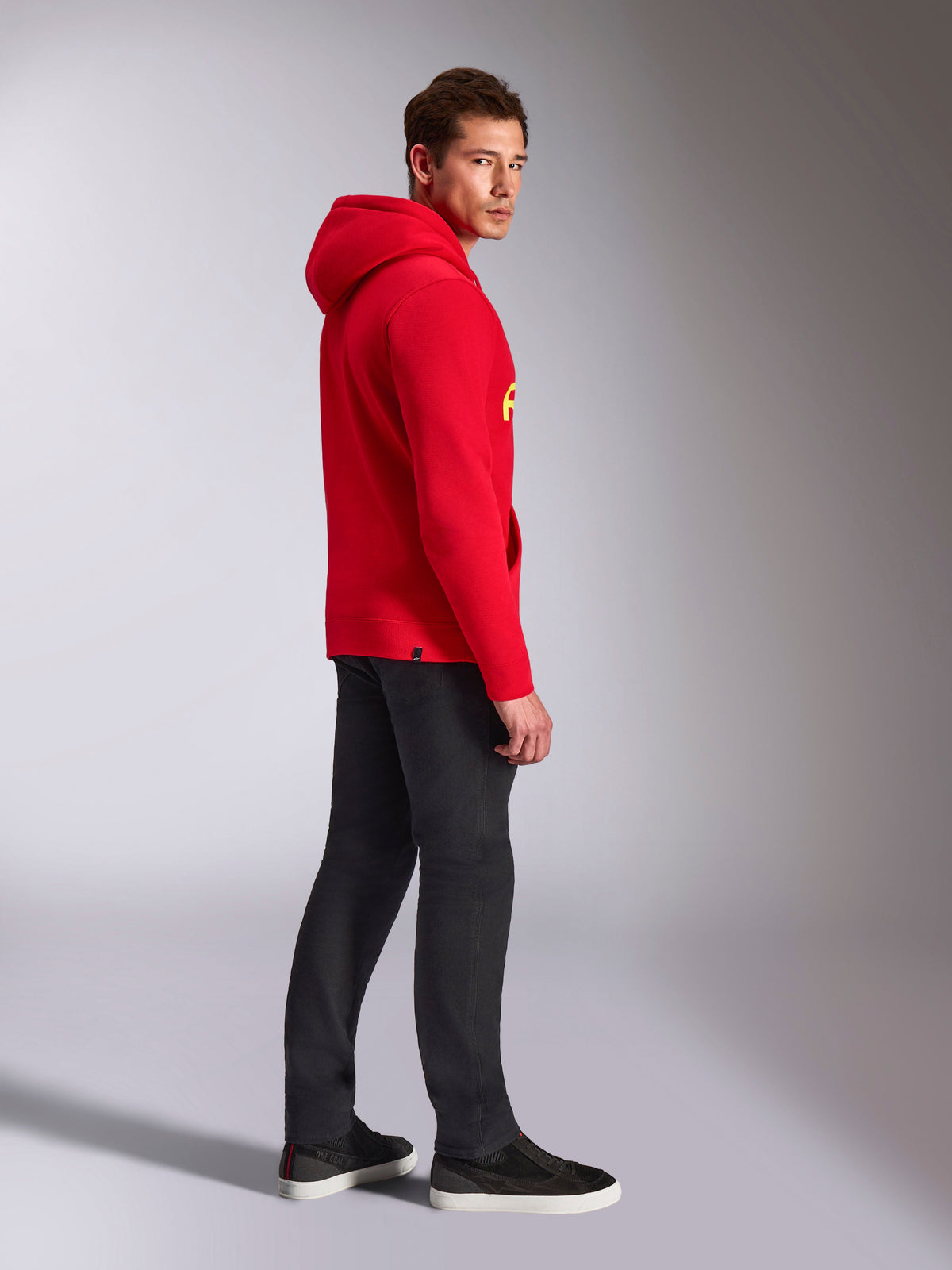 Alpinestars Ride V3 Hoodie, casual sportswear, Red with Hi-Vis Yellow branding, male model wearing red hoodie with black pants and sneakers, side profile view, pullover fleece design with ribbed cuffs and hem.
