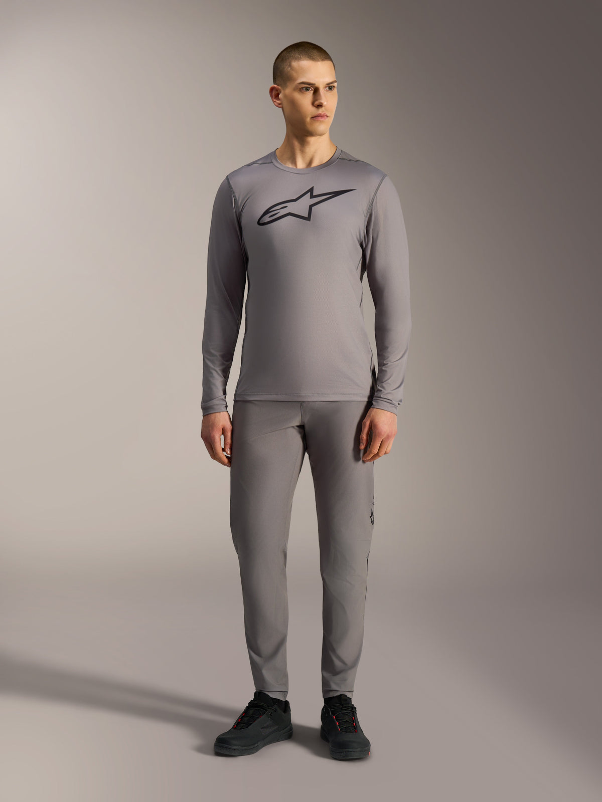 Alpinestars A-Dura Ride Long Sleeve Jersey in Gray, featuring a large black chest logo, worn with matching MTB pants.