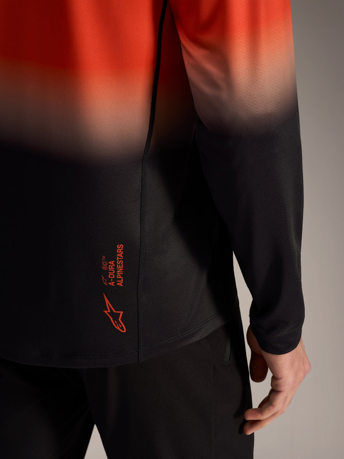 A-Dura ASTARS Jersey 2.0 in orange black gradient, detailing the lower back logo and breathable jacquard fabric.