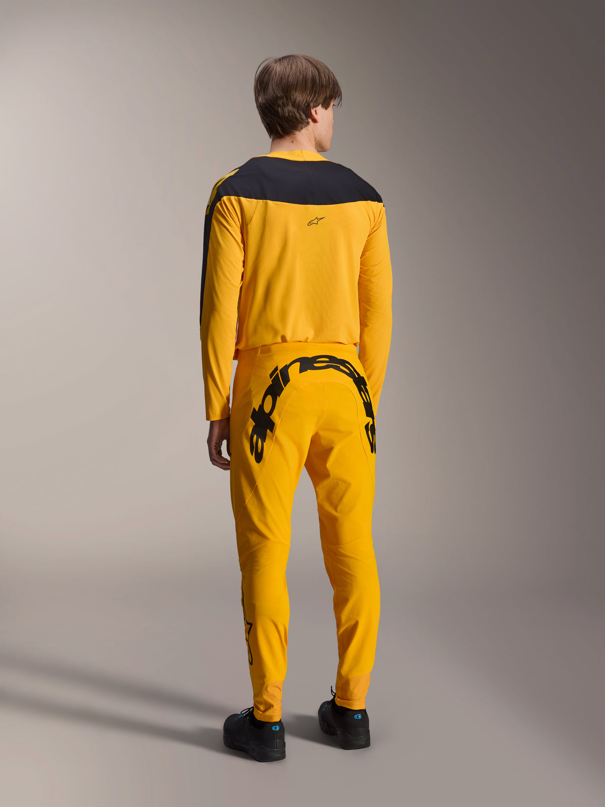 Alpinestars Limited Edition A-Supra Melt Gold Gear-Set, MTB Jersey and Pants, Dark Yellow and Black, rear view featuring large Alpinestars wordmark on the seat and black yoke on the jersey, performance mountain bike apparel