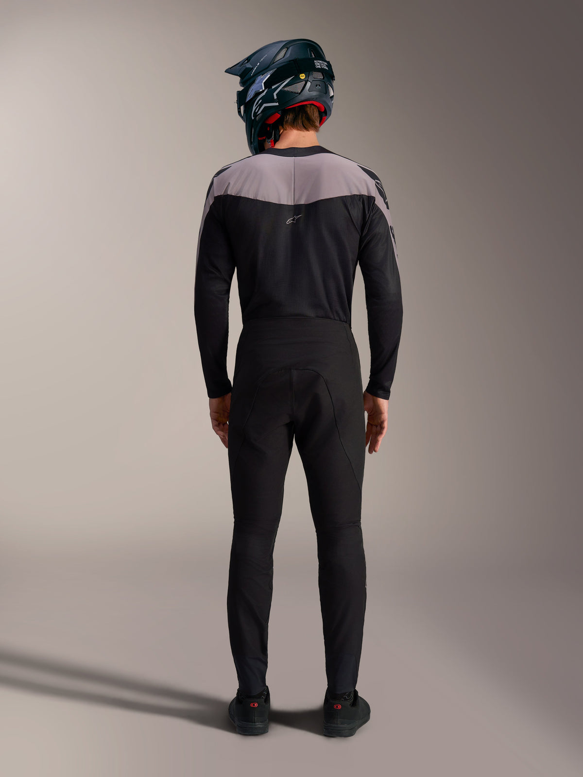 Alpinestars A-Supra Elite MTB kit in black, featuring performance pants and jersey with a full-face helmet, back view.