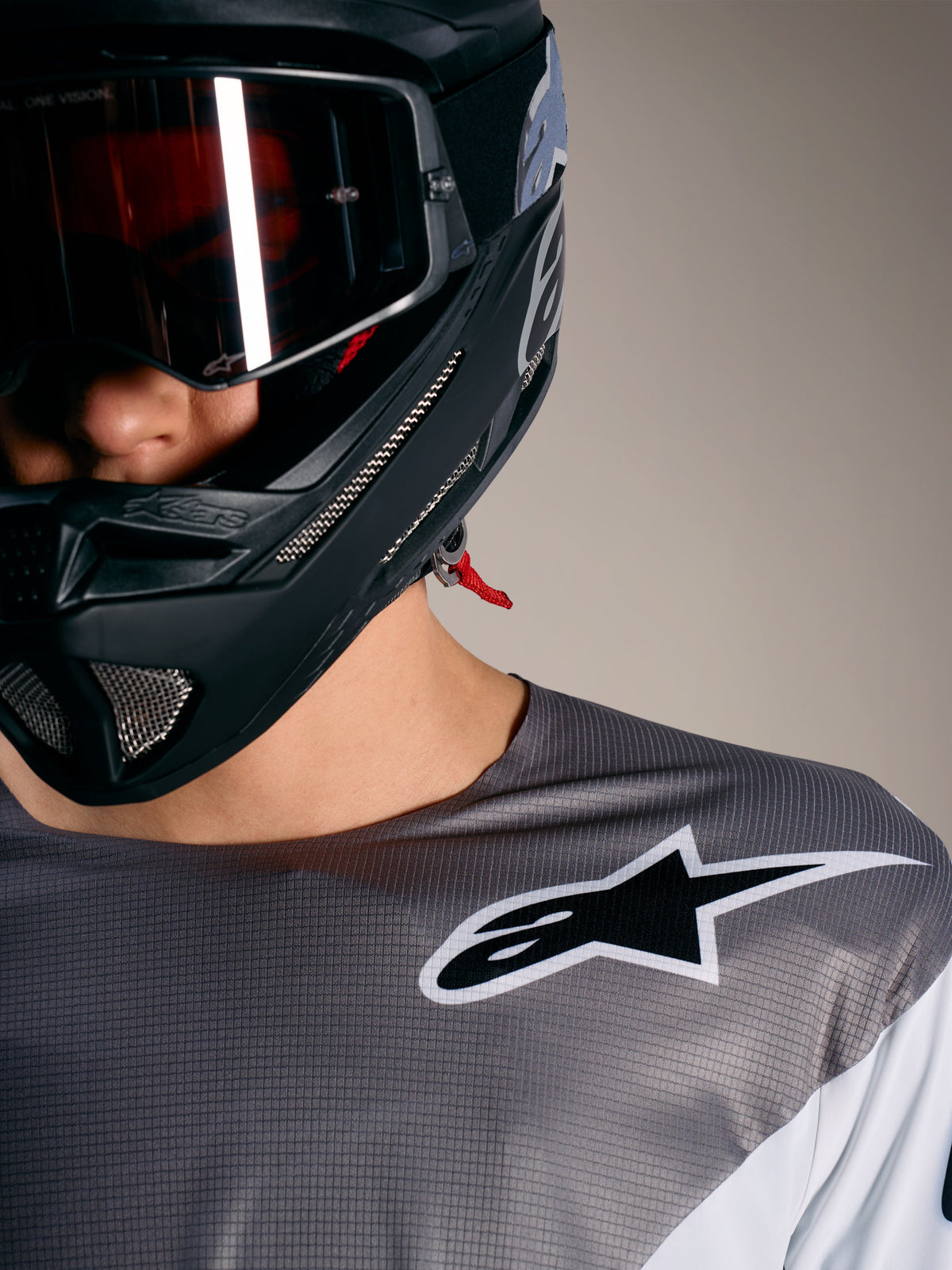 Alpinestars A-Supra Elite Jersey in Faded Gray with white logo, micro-perforated fabric, and black MTB helmet.