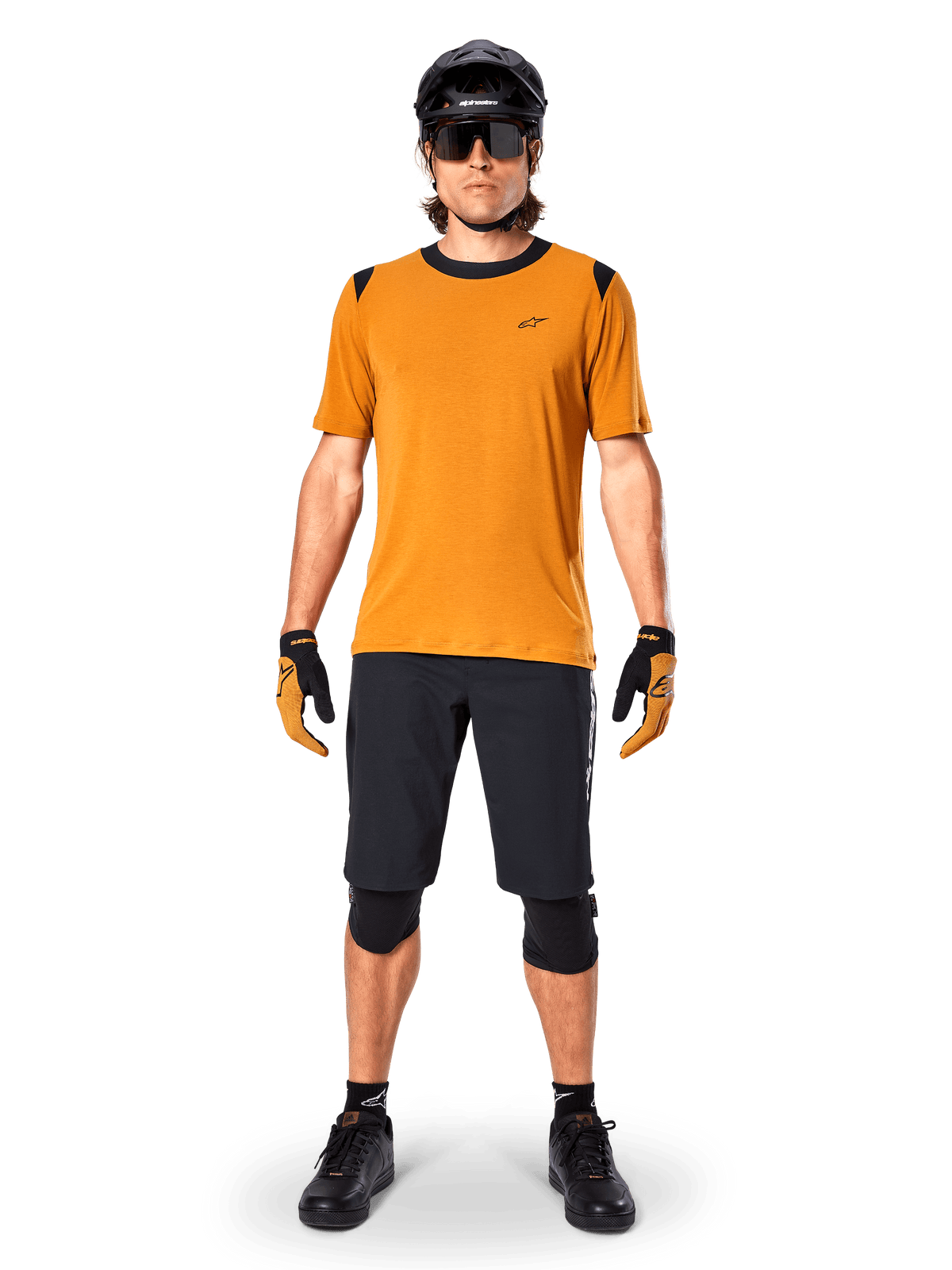 Alpinestars A-Dura Dri Wool Short Sleeve Jersey in Dark Gold, mountain bike jersey worn with black shorts and protective gear, mustard yellow fabric with black collar and shoulder accents, performance cycling apparel for trail riding.