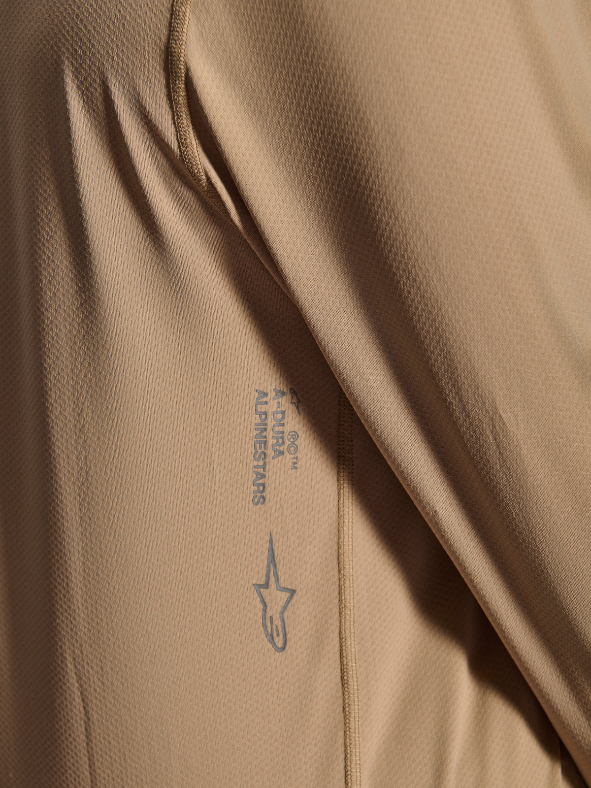 Alpinestars A-Dura Astar Long Sleeve Jersey, MTB Cycling Jersey, Brown, Close-up showing jacquard fabric texture, printed Astars logo and A-Dura wordmark, technical mountain bike apparel