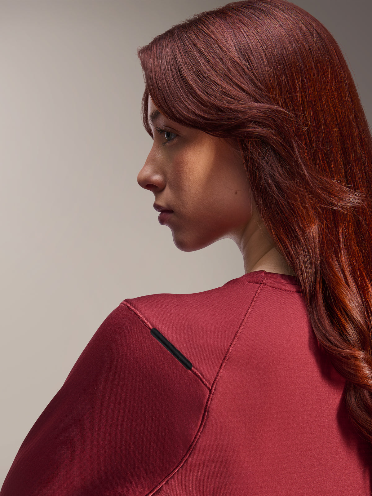 Woman wearing Alpinestars Stella A-Dura Thermal Jersey, Burgundy long-sleeve MTB jersey, close-up side profile view, focusing on shoulder seam detail and material texture, lifestyle cycling gear