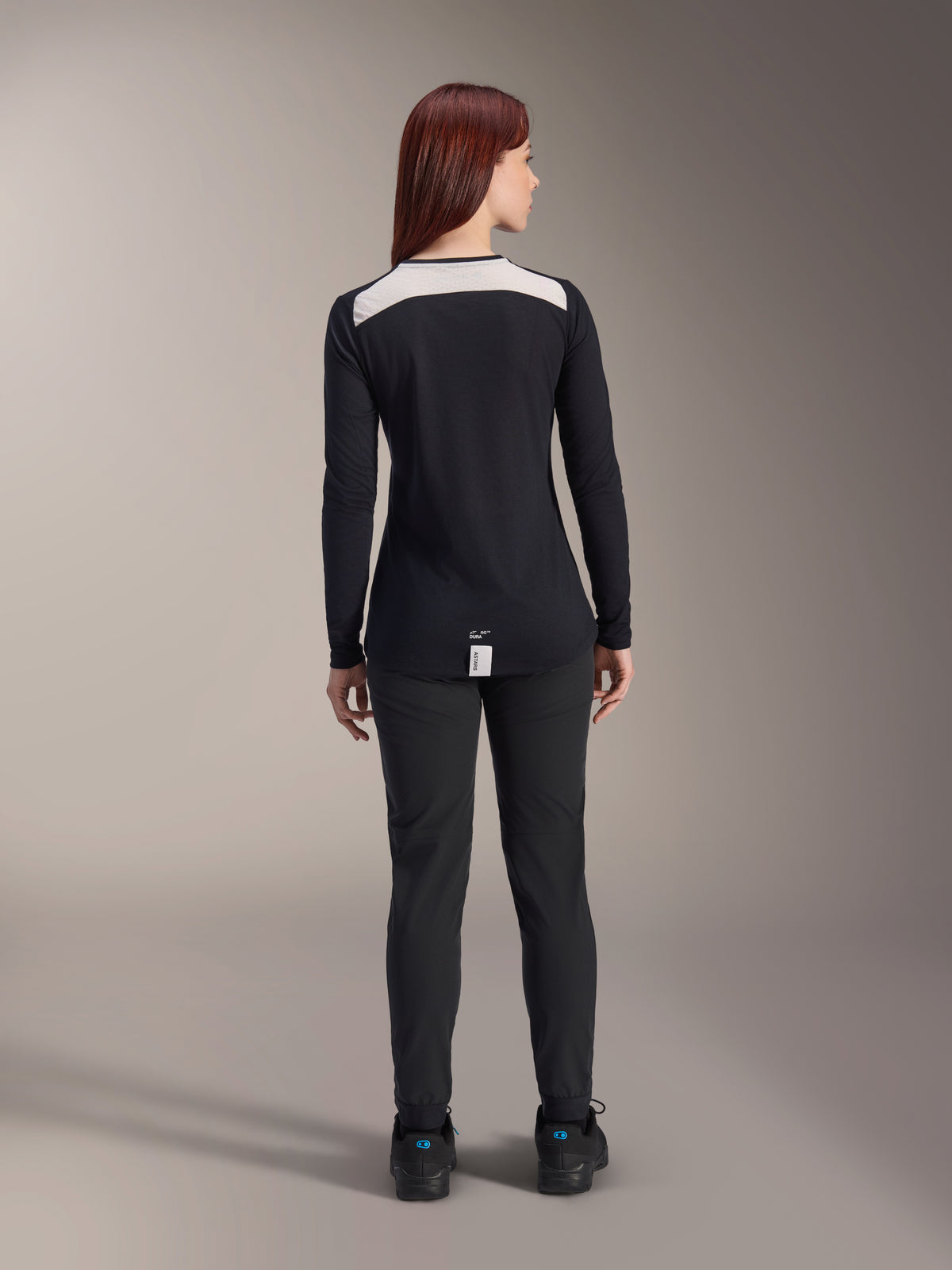 Alpinestars Stella A-Dura Dri Astar Long Sleeve Jersey, Women's Black MTB Jersey, rear view featuring white mesh ventilation panel on shoulders, paired with black cycling pants, technical off-road riding apparel