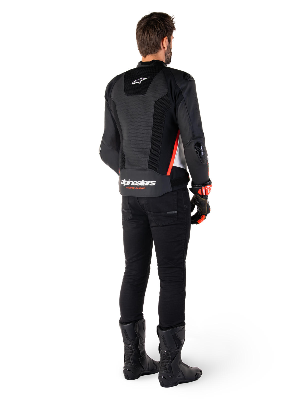 Rider viewed from the back wearing the Alpinestars Missile V3 Airflow Leather Jacket in Black White Red Fluo, styled with black pants and black boots, featuring extensive perforated leather for ventilation, DFS shoulder armor, and prominent Alpinestars branding on the lower back.