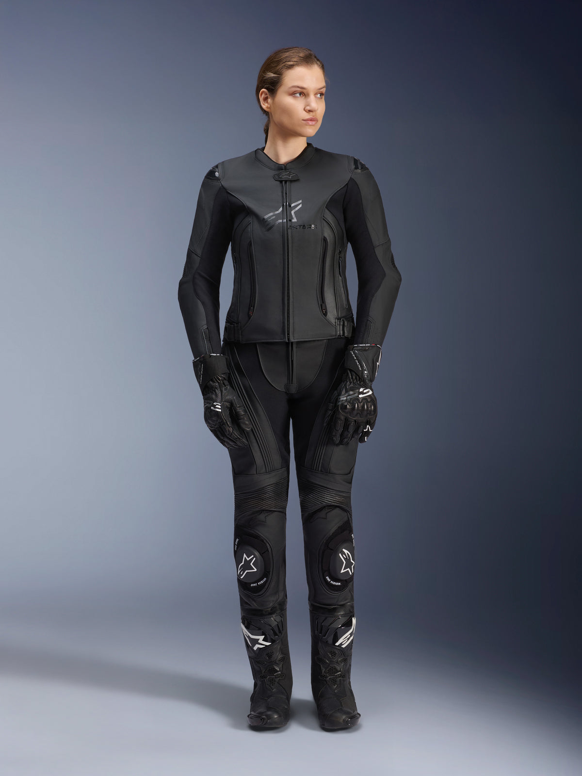 Alpinestars Women Stella GP Plus V4 Leather Jacket in Black Black, worn by a female rider with matching leather racing pants, gloves, and boots, featuring a tailored fit, center zipper, and subtle chest branding, coordinated for sport and road motorcycle riding.