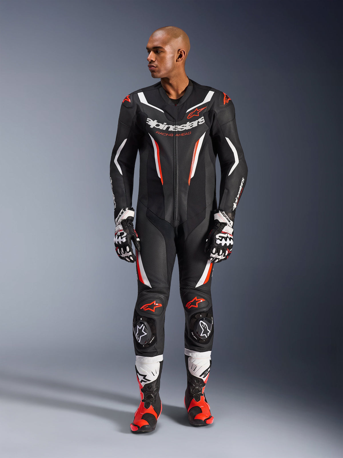 Alpinestars GP Force V2 Leather Suit - 1Piece, Black White and Red Fluo, full-body view of male model wearing professional motorcycle racing gear with matching gloves and boots, featuring perforated leather panels and protective knee sliders.