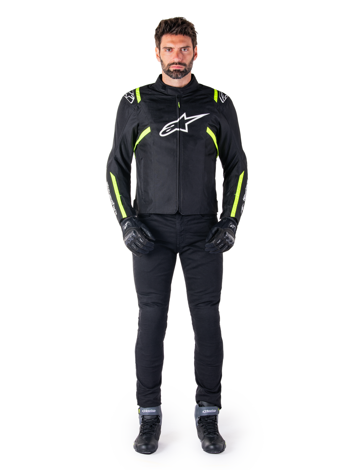 Alpinestars T-SPS V2 Waterproof Jacket, Black White and Yellow Fluo, worn by a model with black riding pants and gloves, featuring a white Alpinestars logo on the chest and fluorescent accents on shoulders and sleeves, sport-cut motorcycle gear