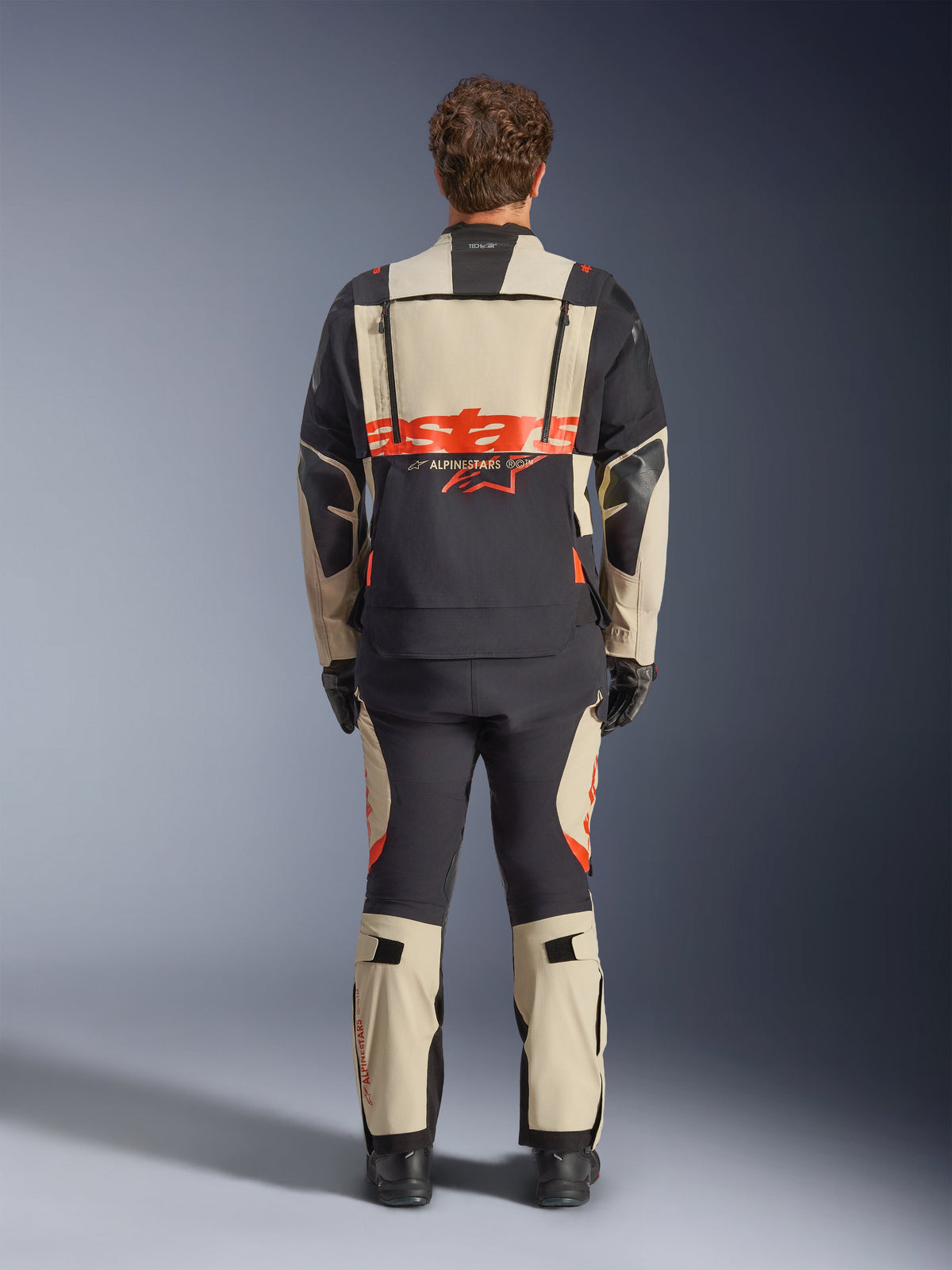 Alpinestars Halo Pro Drystar® XF Laminated Jacket, Adventure Motorcycle Jacket, Mastic Black with orange logo, rear view showing large back branding and modular ventilation zippers, worn with matching adventure pants for all-terrain performance