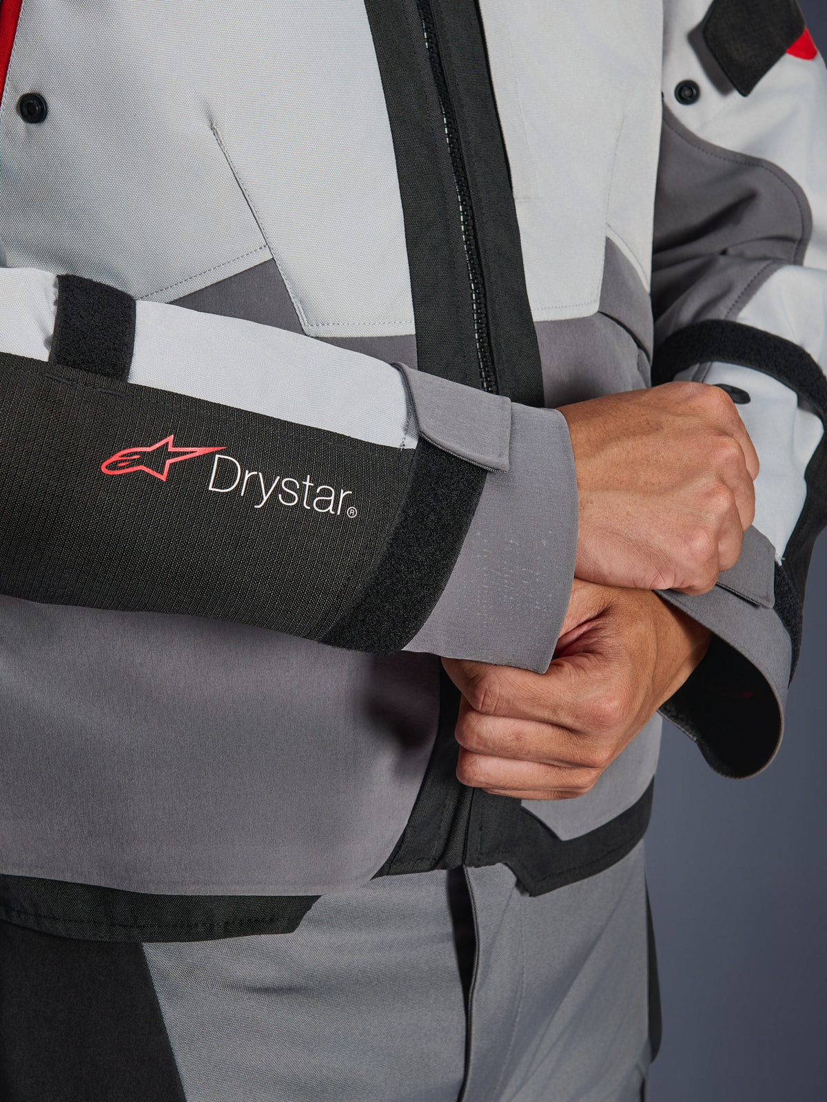 Close-up detail of Alpinestars Andes V4 Drystar® Jacket sleeve, Gray and Black textile, featuring red and white Drystar logo on forearm, adjustable velcro wrist closure, high-performance waterproof motorcycle gear