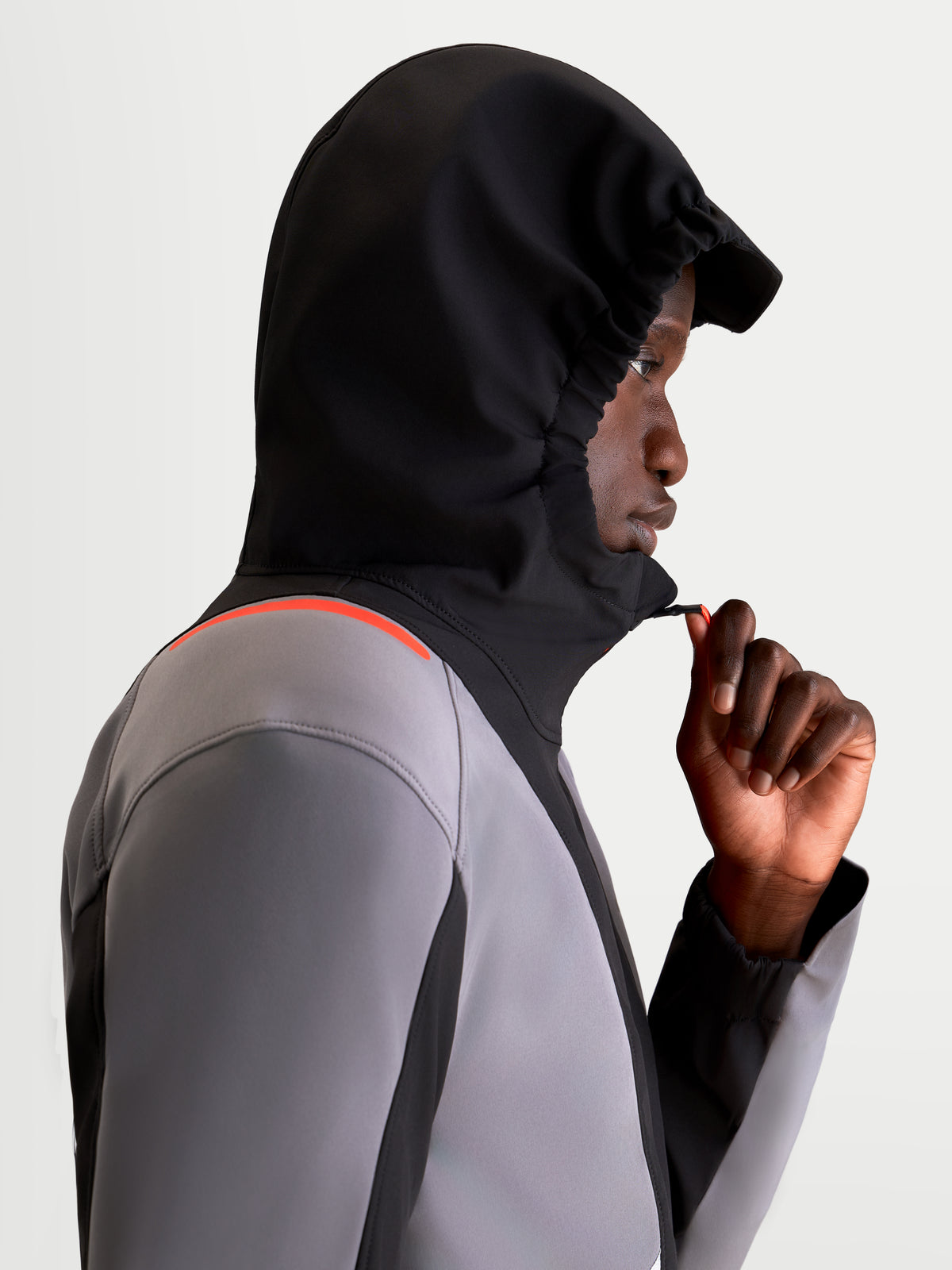 Alpinestars C-5 Drystar Jacket, men's urban contemporary motorcycle textile jacket in black and dark gray, side profile view of a model wearing the waterproof jacket with the integrated hood up and adjusting the front zipper