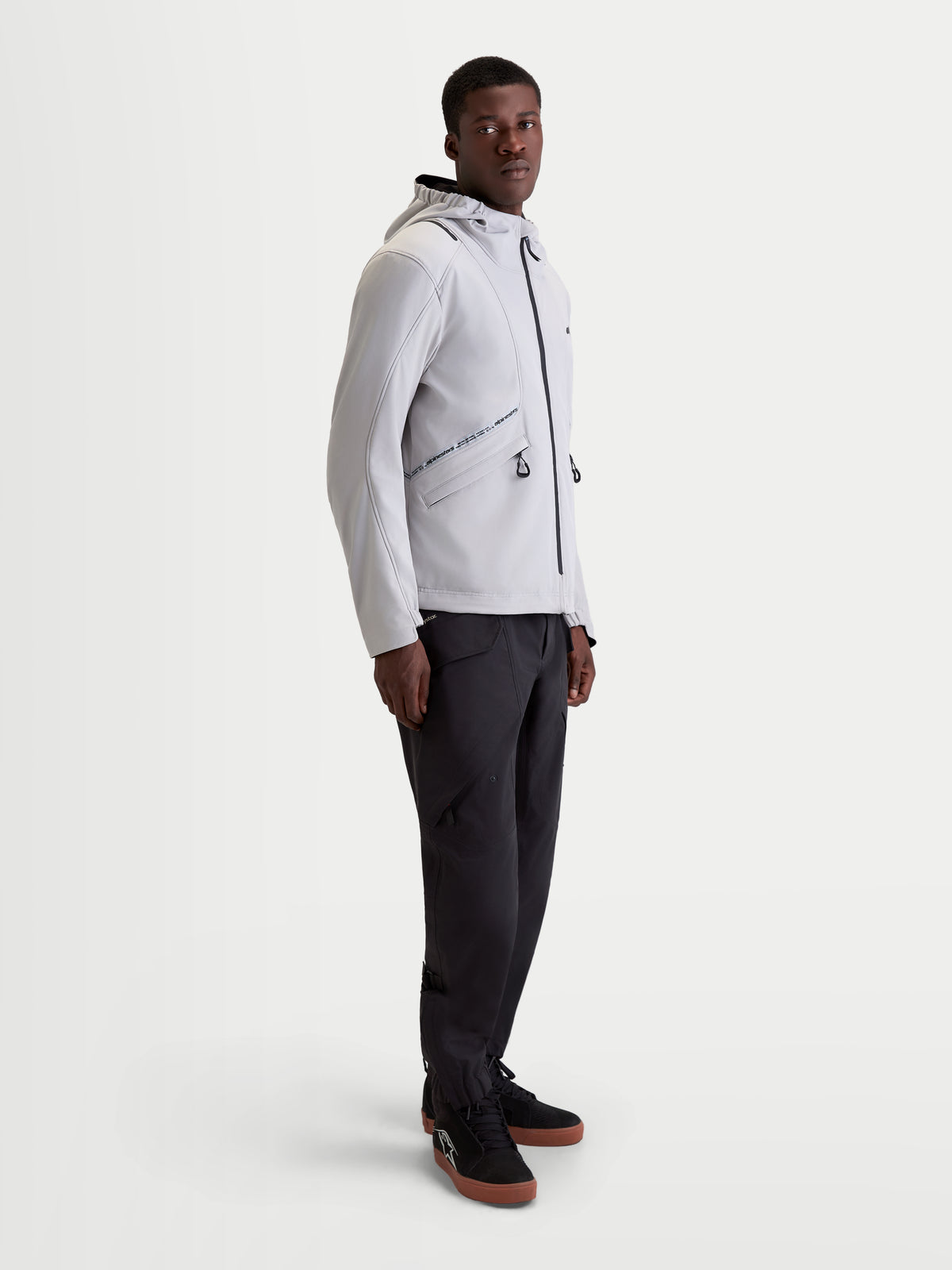 Alpinestars C-5 Drystar® Jacket, men's urban contemporary motorcycle textile jacket in light gray and black, side profile view on a model wearing matching dark pants and riding shoes, waterproof 2-layer softshell construction with integrated hood.