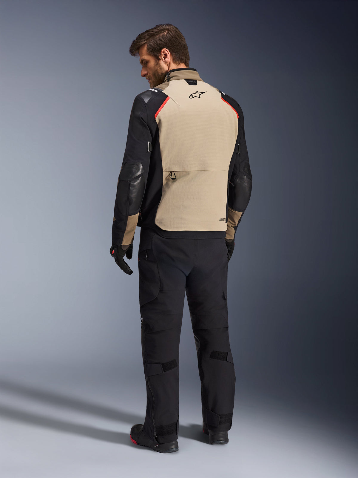 Alpinestars Andes Pro Drystar® XF Jacket, Motorcycle Jacket, Walnut and Black with red accents, back view on model, adventure touring design with large rear storage pocket, worn with black riding pants and gloves.