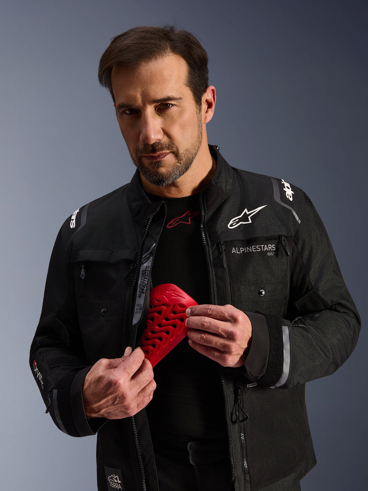 Alpinestars Cusco Drystar® Jacket in black, featuring a red Nucleon Flex Pro armor piece held by a male model.