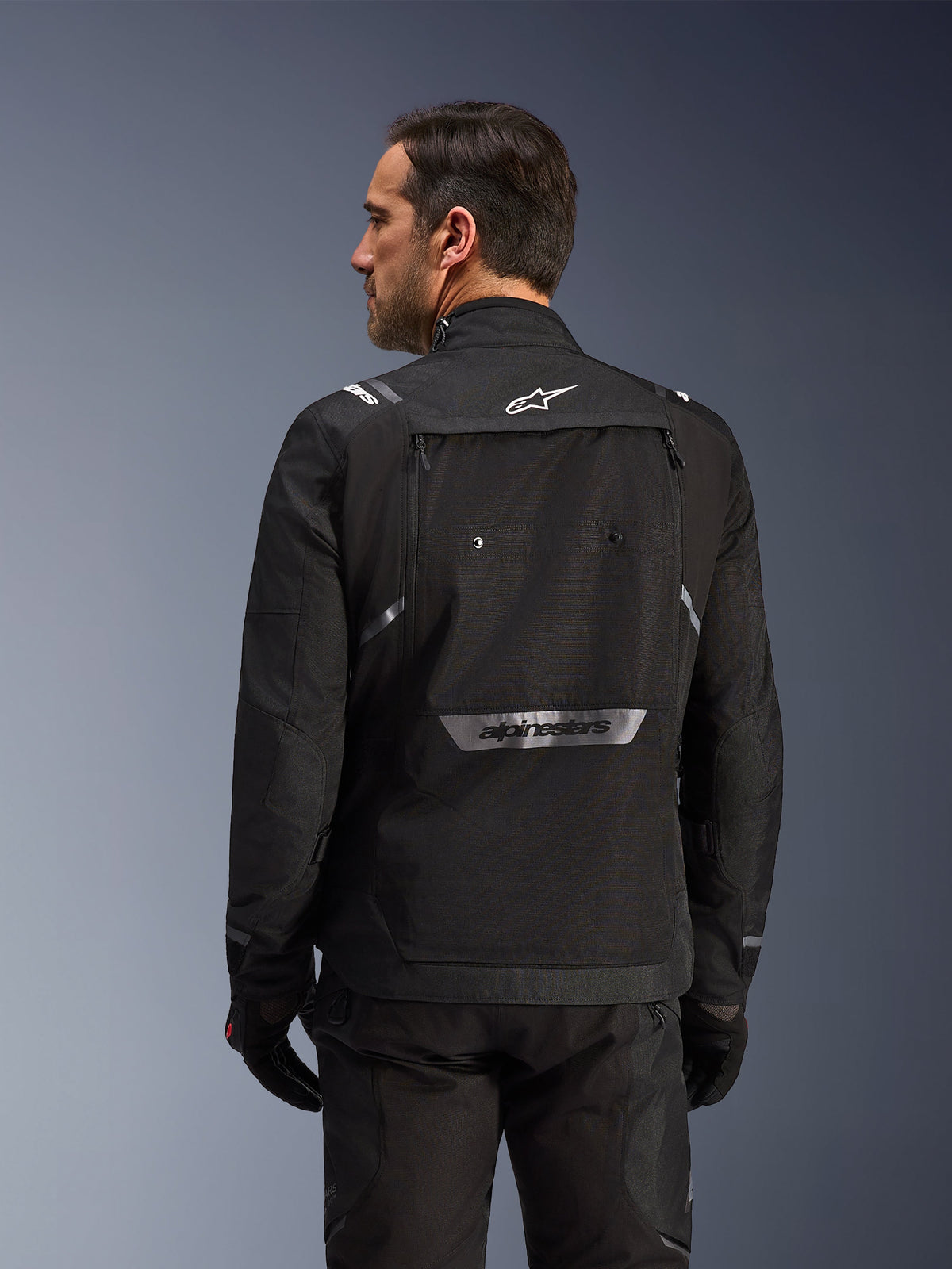 Rear view of the black Alpinestars Cusco Drystar® Jacket for men, featuring a large storage pocket and reflective branding.