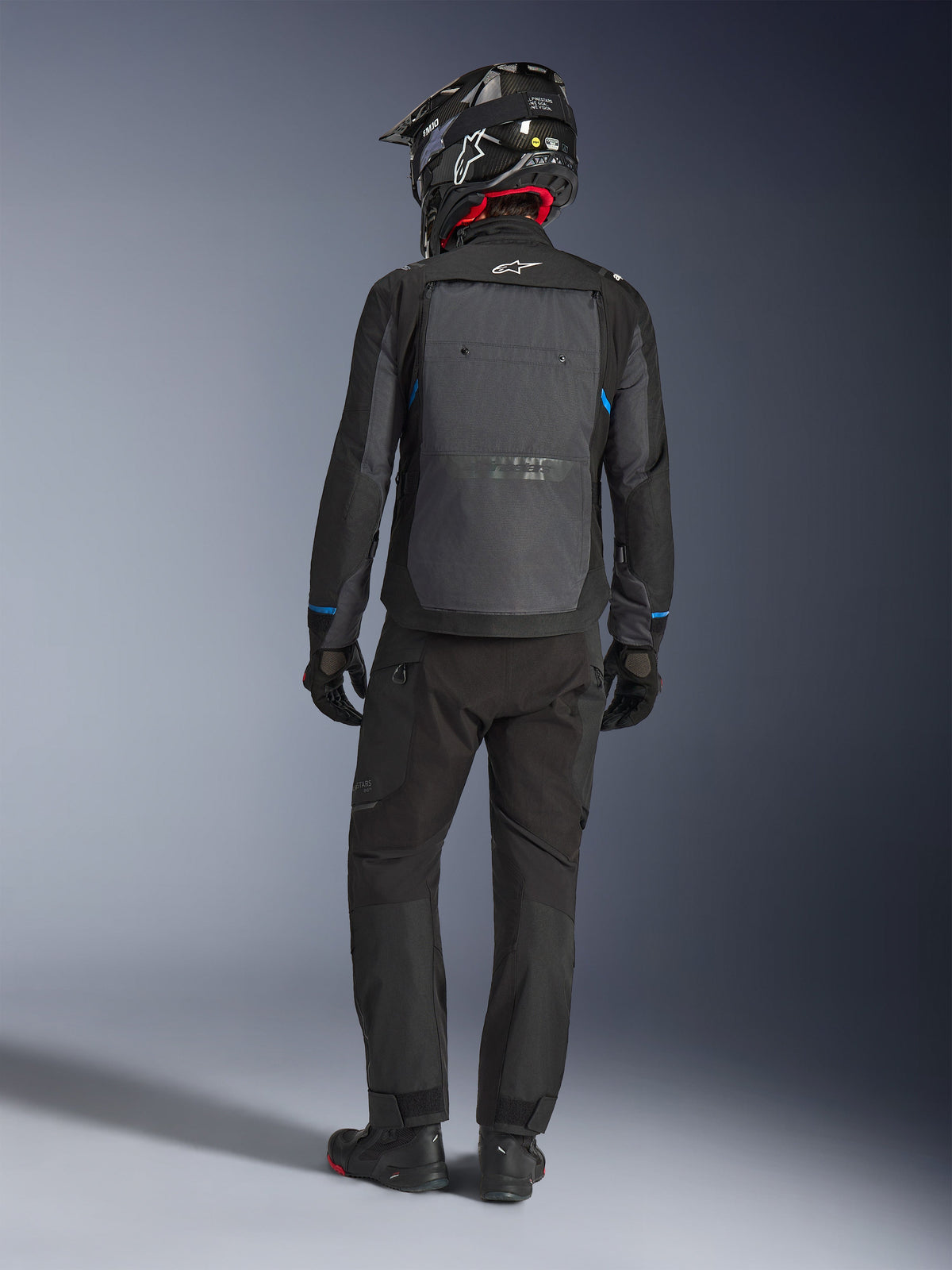 Alpinestars Cusco Drystar® Jacket, Black and Deep Gray, back view of rider wearing full adventure touring gear, large gray back panel with Alpinestars logo, blue sleeve accents, worn with matching black pants and helmet.