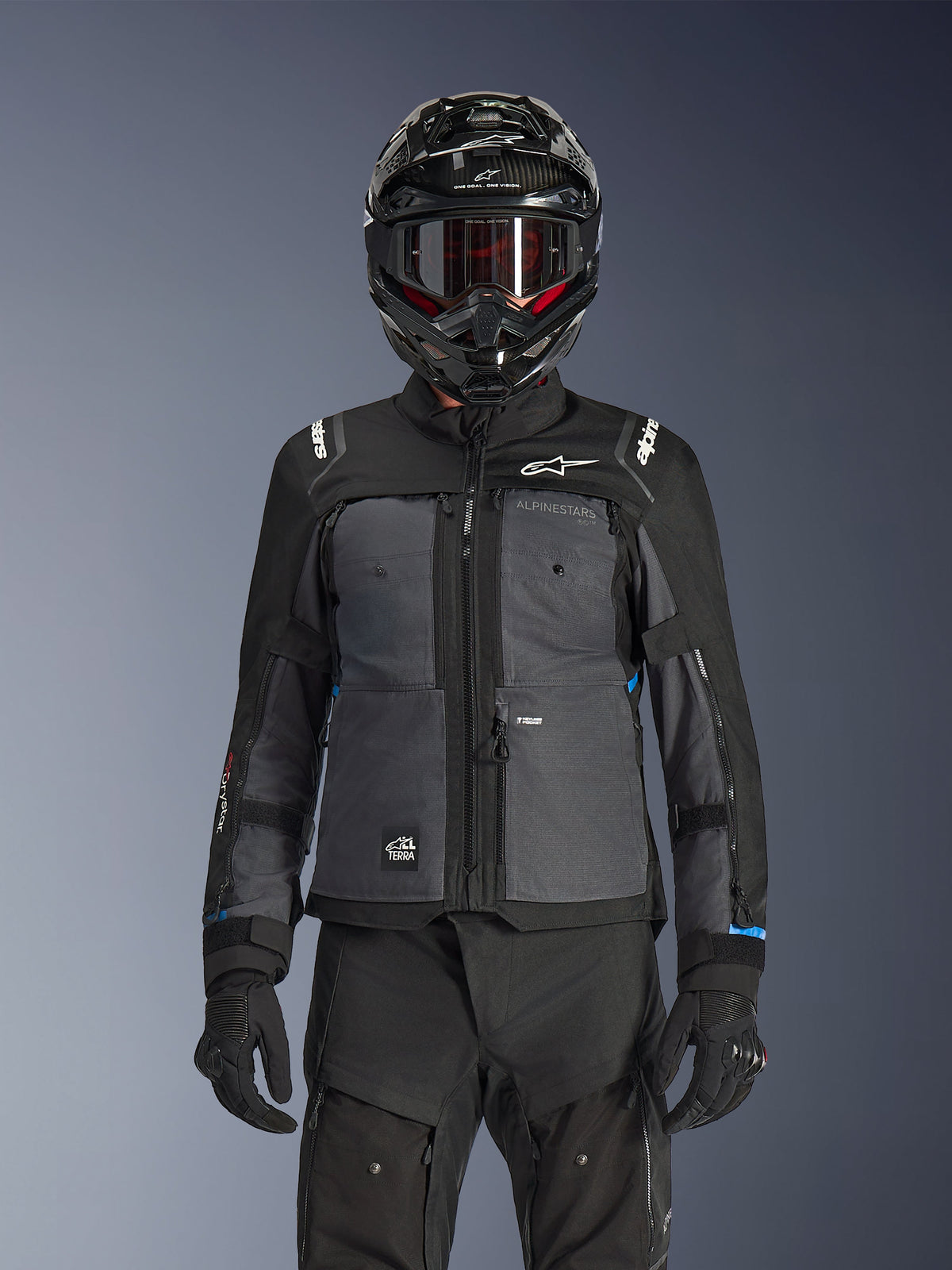 Alpinestars Cusco Drystar® Jacket, Black and Deep Gray, motorcycle adventure touring jacket worn with matching black technical pants and a dual-sport helmet, featuring a two-tone design with ripstop panels and Alpinestars branding