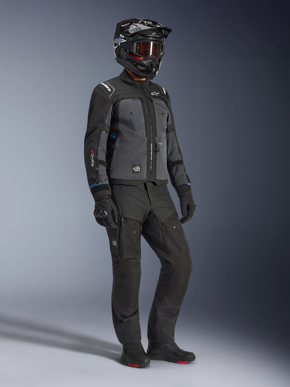 Model wearing Alpinestars Cusco Drystar® Jacket in Black and Deep Gray, paired with full motorcycle riding gear including a black helmet, matching technical pants, gloves, and boots, featuring ripstop and softshell construction for road and adventure touring