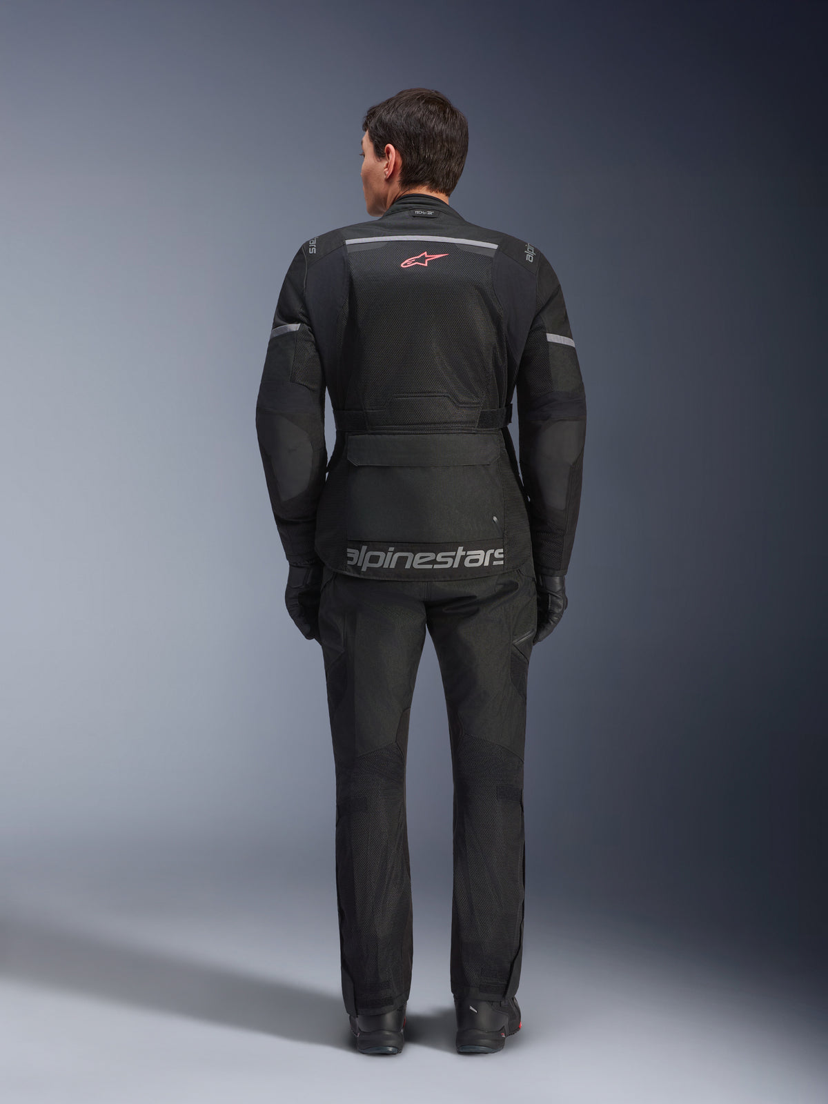 Alpinestars Andes Air Drystar® Jacket and Pants, Black motorcycle touring outfit, rear view of rider, featuring mesh panels, red star logo, and reflective alpinestars branding on the jacket, worn with black gloves and boots.