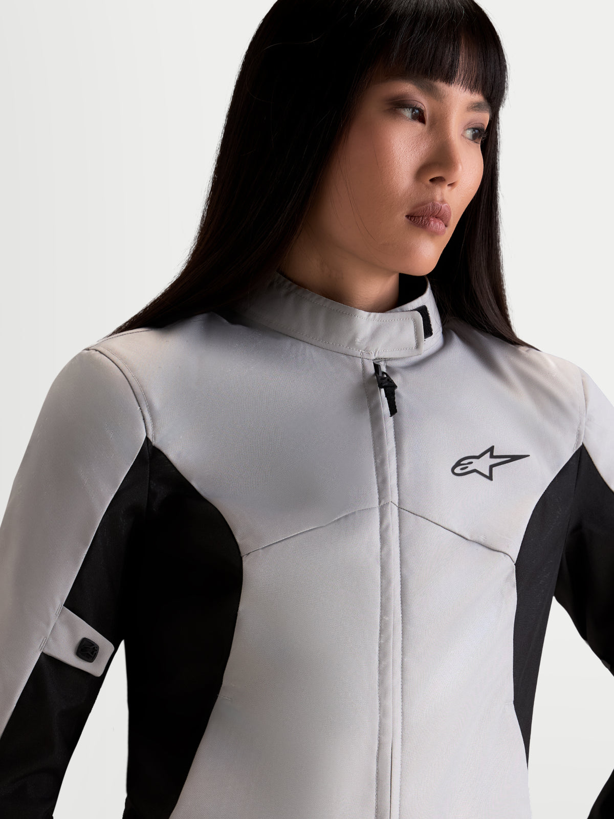 Alpinestars Stella C-1 Waterproof Jacket, women's urban motorcycle commuter jacket in ice gray and black, close-up upper body view showing high collar, waterproof textile construction, and A-star logo worn by a model.