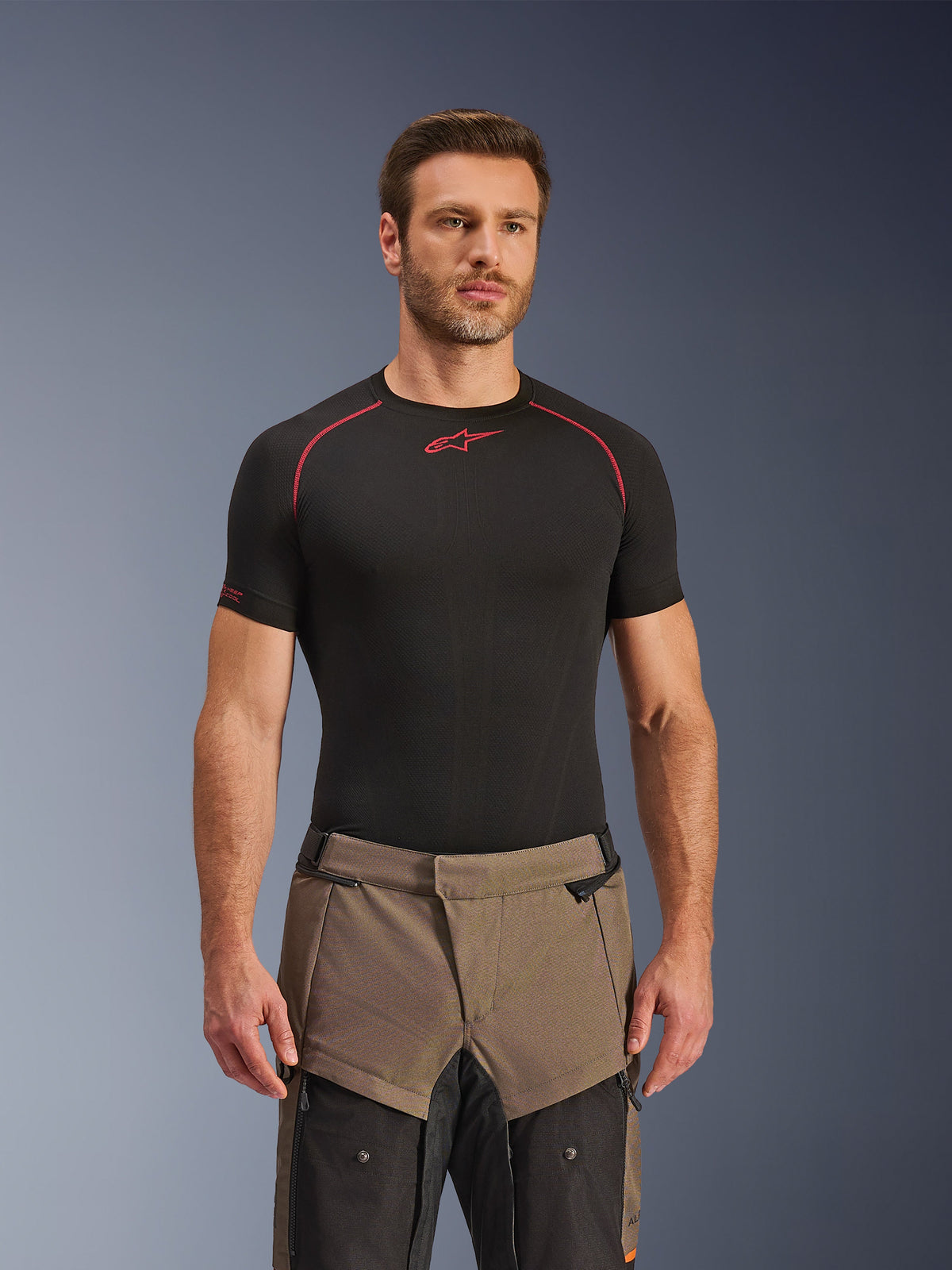 Alpinestars Cusco Drystar® Pants, Walnut Black adventure motorcycle pants, worn by a model with a black Alpinestars base layer shirt, featuring a two-tone brown and black textile design with reinforced panels for touring.