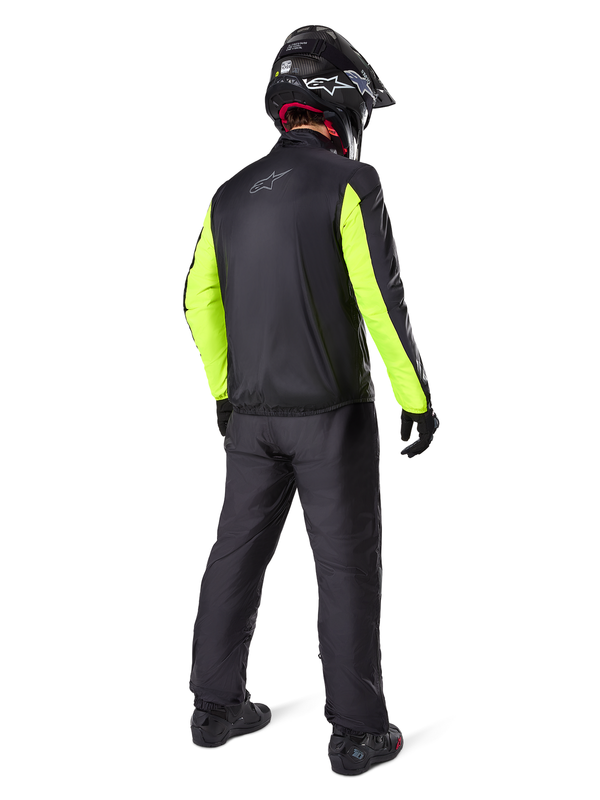 Rider from the rear wearing Alpinestars Bogotá Pro Drystar® 3 Seasons Pants in Black, paired with a black jacket featuring fluorescent yellow sleeves, black adventure helmet, and boots, complete adventure touring gear