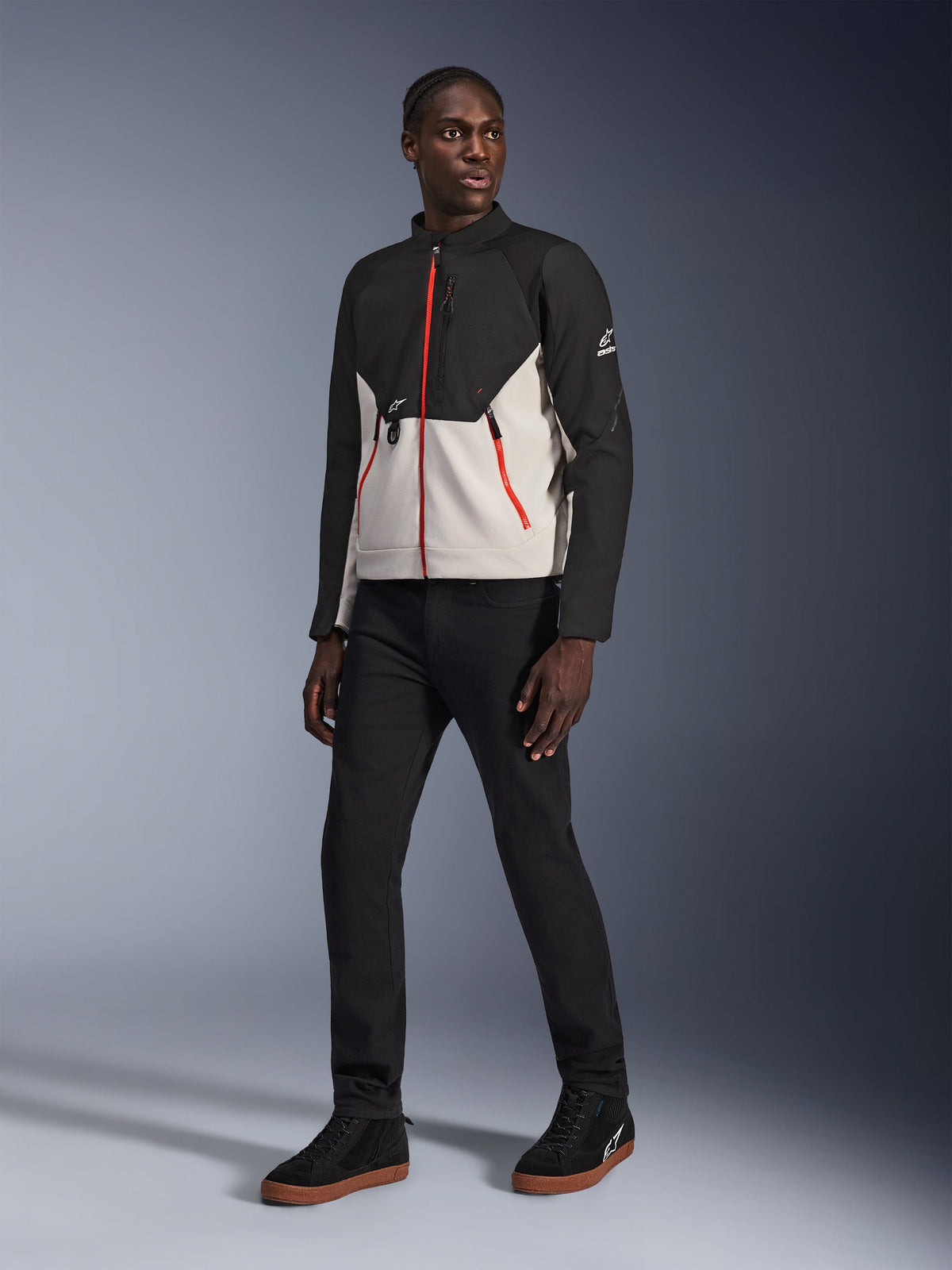 Model wearing the Alpinestars Provoke Jacket in Black Metal Gray, featuring distinctive red front and pocket zippers, paired with black pants and black high-top sneakers with gum soles, urban contemporary motorcycle gear for a street-ready look.