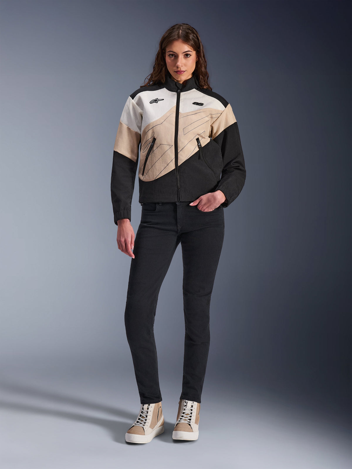 Alpinestars Woman Stella Moshell Jacket, urban motorcycle jacket featuring an asymmetrical Black, Sand, and Off White color-blocked design, worn with black slim-fit pants and tan high-top sneakers, modern streetwear aesthetic for riders.