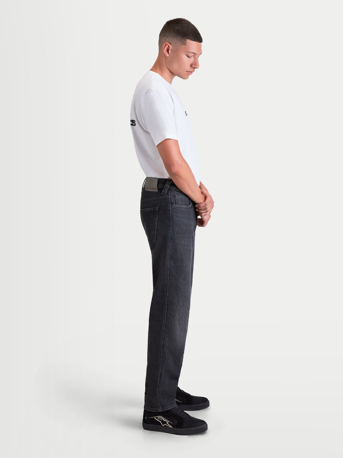 Alpinestars Flex-AST 8 Denim Pants, men's urban contemporary motorcycle riding jeans in Used Black, side profile view on a model wearing a white t-shirt and casual riding footwear, AA-rated protective single-layer denim