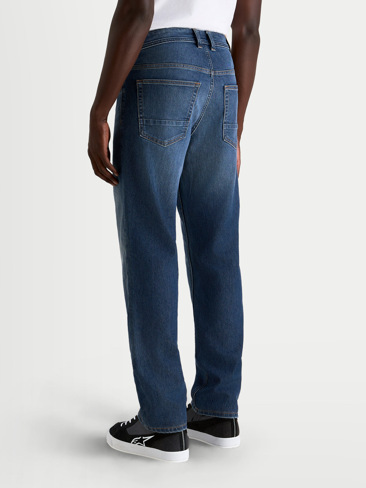 Alpinestars Flex-AST 8 Denim Pants, men's urban motorcycle riding jeans in medium blue, rear view showing single-layer stretch denim construction, five-pocket layout, and regular straight fit worn by a model.