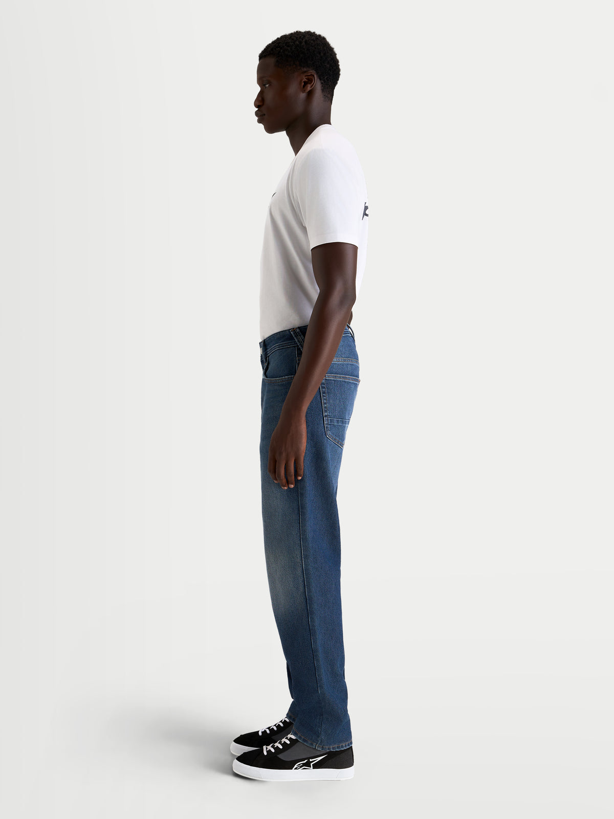 Alpinestars Flex-AST 8 Denim Pants Short, men's urban motorcycle denim pants in medium blue, side profile view worn by a model with a white t-shirt, AA-certified technical riding apparel