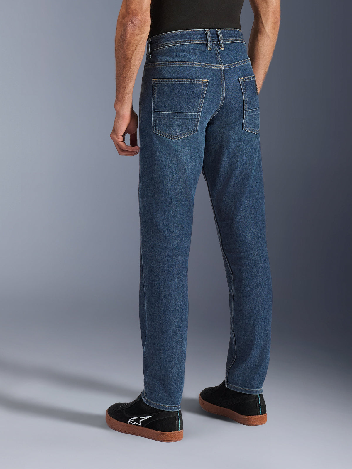 Alpinestars Flex-AST 5 Denim Pants, Men's Urban Motorcycle Riding Jeans in Indigo Washed Blue, back side view on model showing the tapered fit, rear pockets, and casual stretch denim style.
