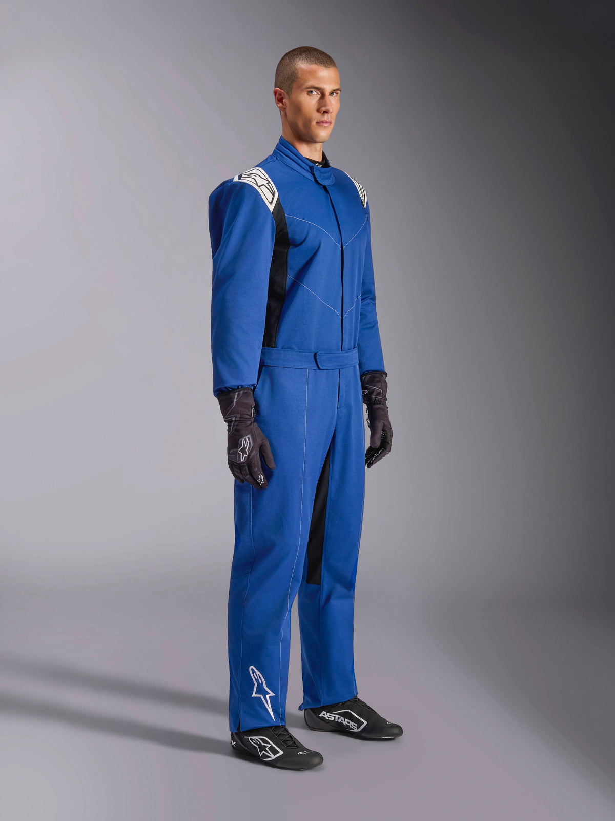 Alpinestars Kart Indoor V2 Suit, Blue Karting Suit, one-piece racing overall with white shoulder panels and logos, adjustable waist belt, white logo on lower leg, worn by model with black racing gloves and shoes, motorsport apparel for indoor karting