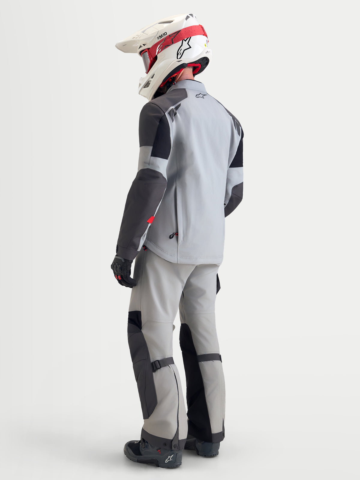 Alpinestars Arenis Gore-Tex Gear Set, men's adventure touring motorcycle jacket and pants in light gray and black, rear three-quarter view on a model wearing matching gear and helmet, waterproof textile construction.