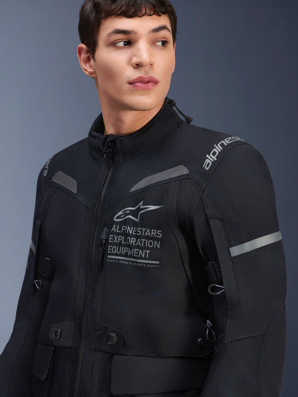 Alpinestars ST-7 2L GORE-TEX Jacket, Motorcycle Jacket, Black and Dark Gray, worn by a male model, featuring Alpinestars Exploration Equipment branding on the chest, reflective gray accents, and adventure-ready textile construction