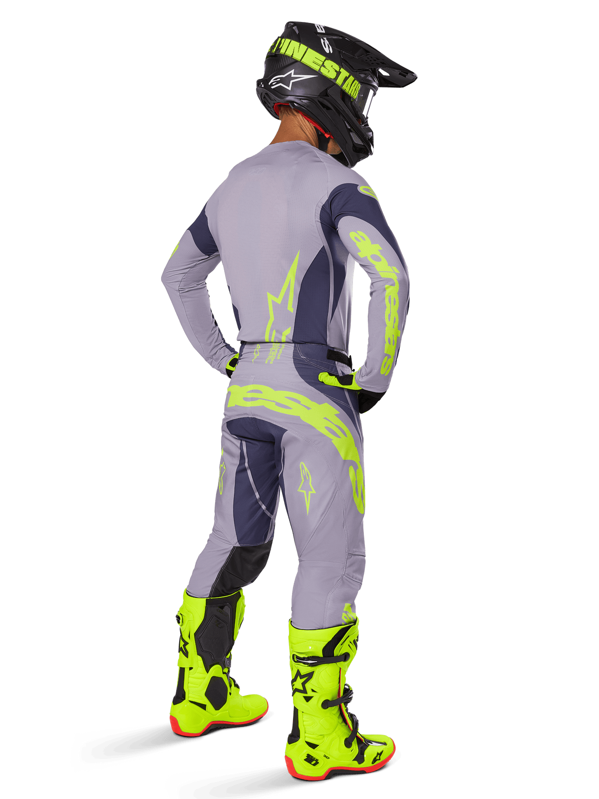 Motocross rider seen from behind wearing full racing gear, including Alpinestars 2025 Techstar Dreem Pants in Gray and Dark Gray with bold neon yellow accents, matching gray jersey with neon graphics, bright neon yellow boots, and black helmet, coordinated professional motocross outfit