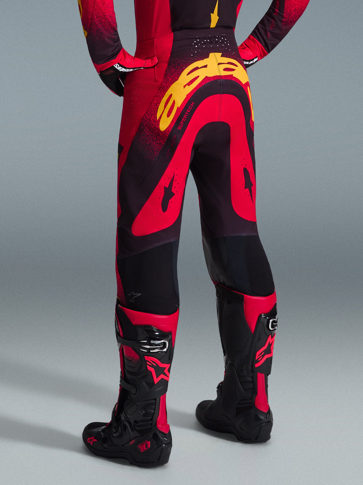 Alpinestars 2026 Supertech Scenz Pants, Motocross Pants, Red Black and Yellow, rear view showing large yellow Alpinestars branding on the seat, worn with a matching jersey and red and black motocross boots.